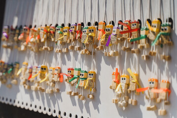 Row of cute handmade wooden doll magnets or keychains with colorful ribbons at a souvenir street market shop