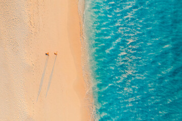 Romantic couple walking along tropical Mediterranean beach at sunset with calm ocean waves soft sand idyllic summer vacation travel destination serene nature scenic paradise seaside background