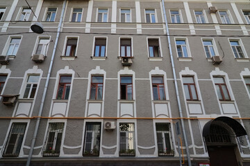 Obraz premium Facade of a multi-story building with a classic architectural style. Exterior is painted in light grey tone with white decorative elements