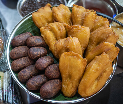Traditional Indonesian street food featuring pisang goreng fried banana and timus ubi ungu purple sweet potato fritters served on banana leaf. Authentic local snack and cultural cuisine concept