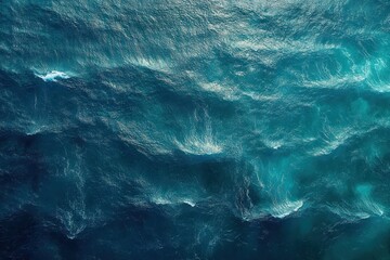 aerial view of deep blue and turquoise ocean waves with rippling surface and shimmering light, evoking serene power and vast open water