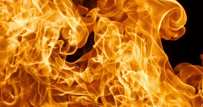 Vibrant close-up of swirling orange fire flames against a dark black backdrop, capturing dynamic heat and motion in abstract fiery texture. Shot on super slow motion camera 1000 fps.