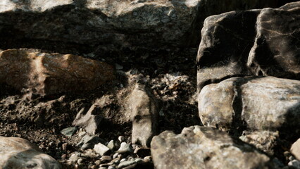 Stunning natural textures reveal the beauty of a rocky shoreline. Jagged stones are scattered on...