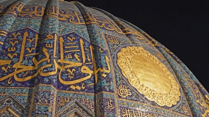 Ornate dome with blue mosaic tiles and golden Arabic script bathed in soft light