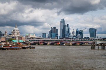 Panorama of London with Blackfriars Bridge, St. Paul's Cathedral and modern skyscrapers reflected on the banks of the Thames.