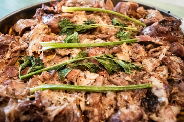 Close-up of homemade oven-baked pork knuckle pieces garnished with fresh celery, representing rustic comfort food and tradition