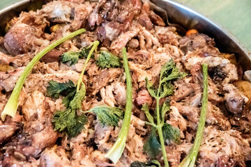 Close-up of homemade oven-baked pork knuckle pieces garnished with fresh celery, representing rustic comfort food and tradition