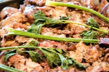 Close-up of homemade oven-baked pork knuckle pieces garnished with fresh celery, representing rustic comfort food and tradition