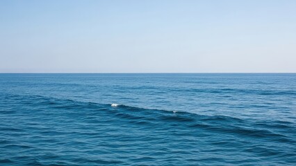 Obraz premium Vast expanse of deep blue ocean under a clear bright sky.