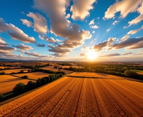 Fototapeta premium Majestic Sunset Over Golden Fields and Lush Green Valleys with Dramatic Cloudscape in a Rural Landscape