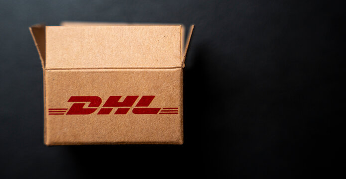 Rzeszow, Poland - Jan 6, 2026: A DHL logistics cardboard box on a dark surface highlights efficient parcel delivery service. Ideal for business and shipping representations.