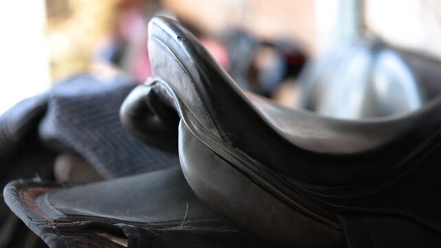 Detailed close up of a leather saddle for horses, showing quality material, shape and classic equestrian tack in a stable