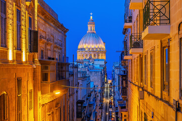 Naklejka premium Valletta, Malta. Street that leeds down to the Grand Harbour and St Paul's Cathedral's dome.