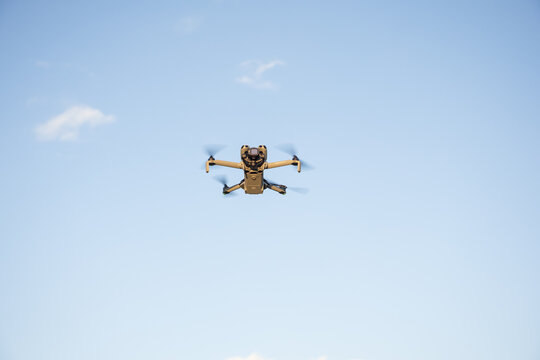 Hamburg, Germany - September 30, 2025: Small Consumer Drone DJI Mini 5 Pro in Flight Against Blue Sky- Low Angle Wide Shot with Copy Space