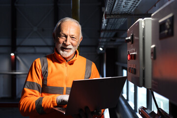 Senior engineer working on laptop at industrial plant