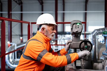 Senior worker inspecting valve in industrial plant