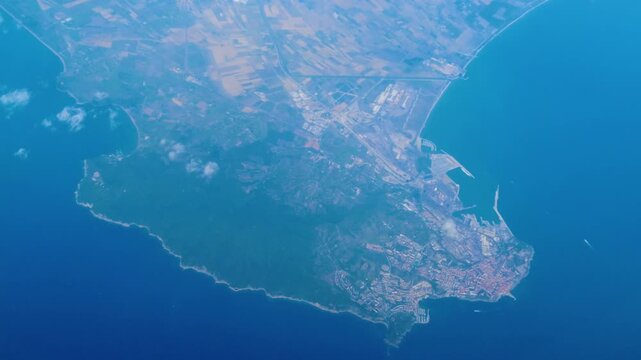 coastal city spreads across rugged peninsula industrial docks road networks dense urban clusters meet deep blue sea along sharply defined shorelines urbanization maritime port 