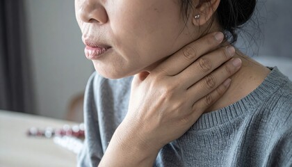 Flu Discomfort Concept: Close-up of hand touching neck with medicine on table

