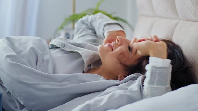 Caucasian smiling woman wake up in bed stretching awaking stretch smile indoors in cozy domestic bedroom home lady female girl morning enjoy comfortable pillow blanket mattress comfy holiday daylight
