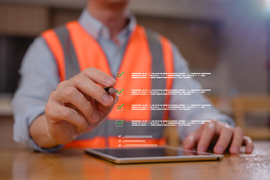 Engineer in safety vest operating tablet with virtual checklist on construction site. Construction engineer inspects project. Safety gear, project management, quality control. Reviewing compliance