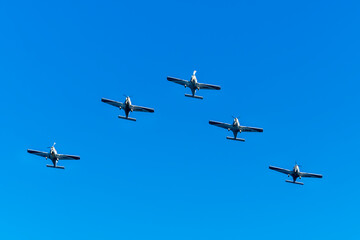 Fototapeta premium Airshow performance with aircraft, flight of pilotage team with colorful smoke trails. Planes and jets in the air. Flight show of air force team with group of planes in blue sky.