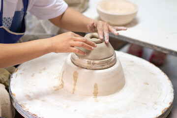 Fototapeta premium Close-Up of Artisan Hands Refining Ceramic Bowl Shape on Pottery Wheel During Production