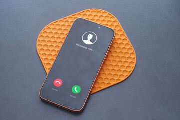 Incoming call interface displayed on modern smartphone on a table. Concept of mobile communication, phone call notification, digital contact and customer support.