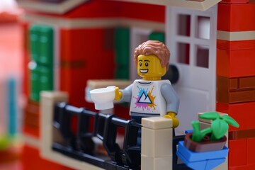 Obraz premium Tambov, Russian Federation - January 04, 2026 A Lego man minifigure standing on a balcony with a cup of coffee.