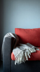 Gift on sofa with blanket in lower frame, vertical airy composition with copy space.