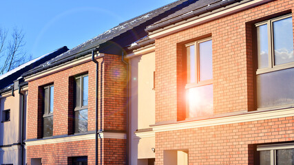 Obraz premium Terraced residential homes with modern facade in newly developed housing estate. The real estate market in the suburbs. New terraced houses in a new development area.