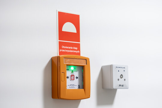 Krakow, Poland - November 30, 2025: Orange fire alarm button with green light, red sign 'Opening fire dampers', crucial element for public building safety