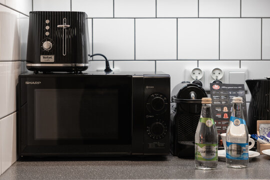 Krakow, Poland - November 30, 2025: Tefal toaster on Sharp microwave, coffee maker, water bottles, kettle on modern counter for amenities
