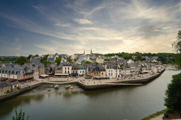 View of the historic port of Saint-Goustan in Auray, featuring traditional stone houses along the riverbank, small boats at low tide, and a lively waterfront that reflects Breton maritime heritage