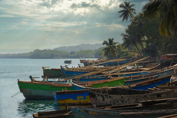 Wooden boats anchored by the river with dramatic sky background.
