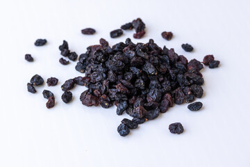 A heap of organic black raisins (dried sweet dark grapes) isolated on a white background. Close-up view of healthy sun-dried currants, perfect for food industry and nutrition concepts.