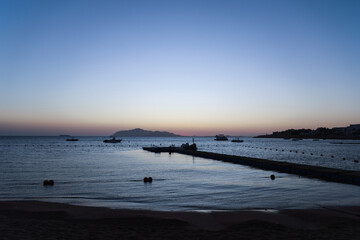 The sun rises over the sea behind Tiran Island in Egypt.