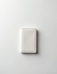 Closed white leather passport holder lies flat on clean white surface. Minimalist object for secure travel documentation storage. Sophisticated, plain accessory for modern globetrotters. Safe