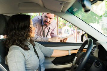 Driving instructor explaining road rules to an adult student driver during a lesson, learning to drive a vehicle