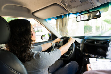 Woman learning driving skills from instructor during a car lesson, preparing for her road test