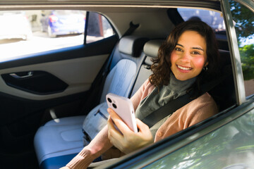 Woman smiling and using smartphone in back seat of rideshare car, traveling and commuting with mobile app