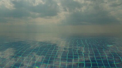 Calm infinity pool water surface with soft reflections and cloudy sky, minimal abstract scene with blue tiles, tranquil mood and large copy space - Powered by Adobe