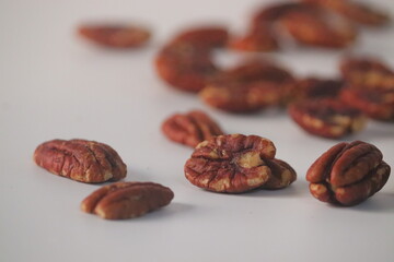 Pecan nuts presented in a natural scatter, featuring shelled pecan halves on a light surface