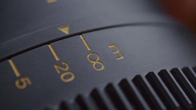 Extreme close-up view of engraved aperture values on turning camera lens ring, arrow moving through markings and stopping at infinity symbol