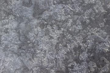 Frozen water with crystals of various shapes. Gray background. Top view.