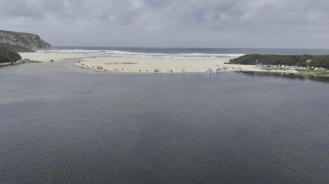 Drone flies south from Groot River over beach to the end of the Otter Trail on a sunny day in Nature's Valley, South Africa