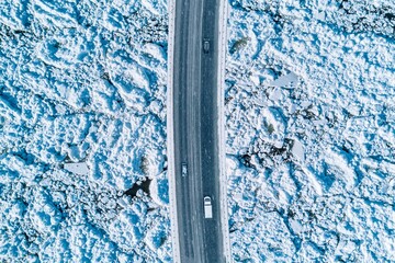 Aerial View of a Snow-Covered Road Traversing a Frozen Landscape with Vehicles Above