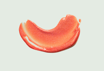 Glittering orange red metallic holographic shimmering lip gloss texture swatch on neutral grey...