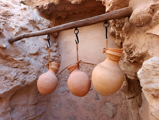 Three traditional Omani clay pottery jugs hanging on the ropes in the street of Nizwa, Oman
