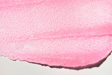 Fototapeta premium Macro texture of shimmering pink lip gloss. Beauty product sample swatch with sparkling particles and glossy finish, isolated on white background