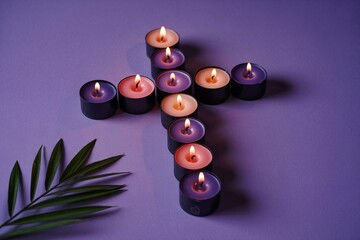 Purple candles arranged in cross shape on purple background with green leaf religious concept with lit with faith